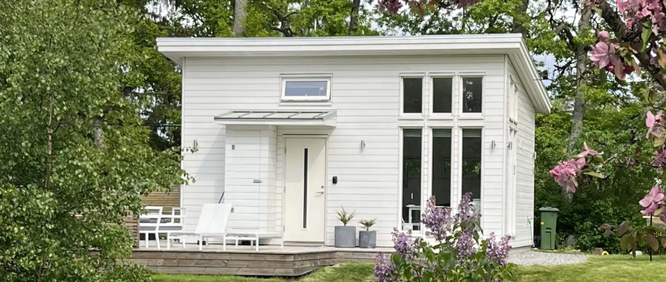 Årehuset 30 vitmålad fasad med stora fönster och altan