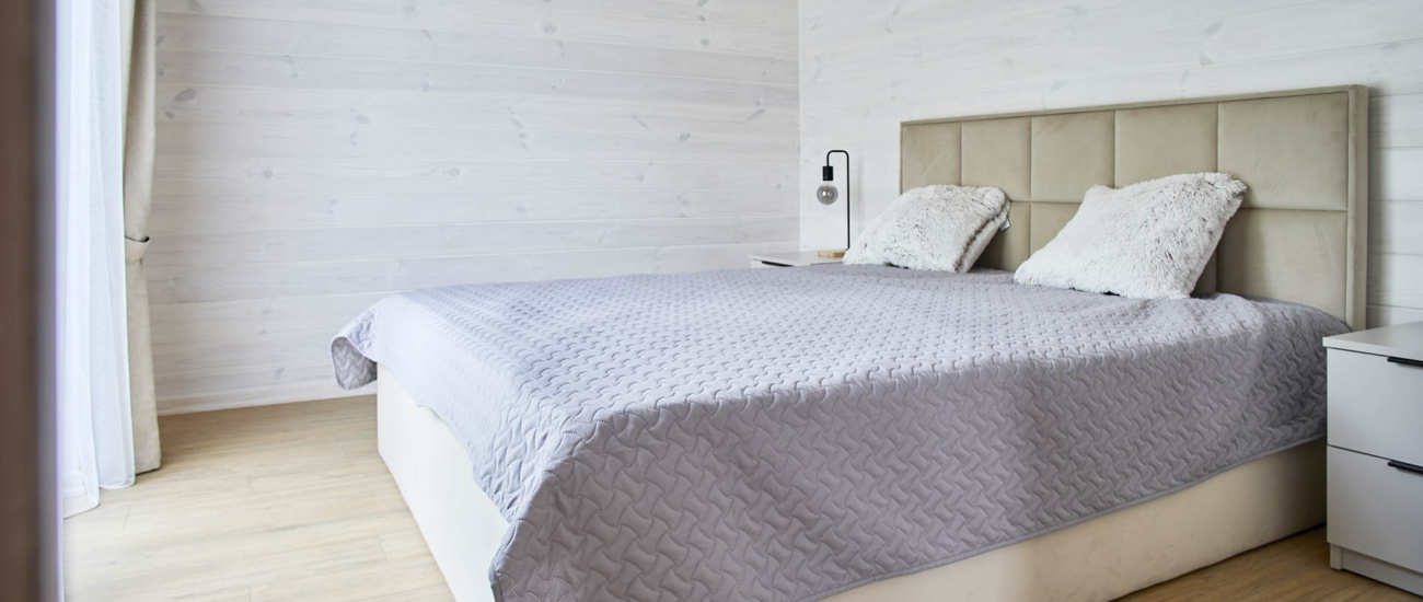 Sovrum med dubbelsäng och ljus träpanel i Saltsjöhus 30 Modern