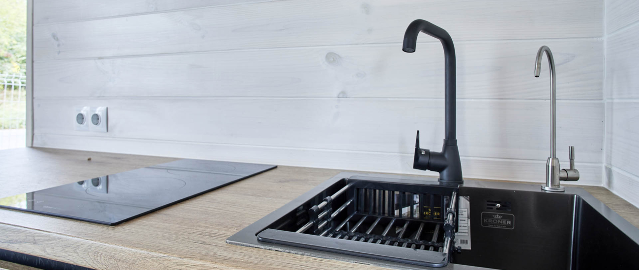 Kök med induktionshäll och svart blandare i Saltsjöhus 30 Modern